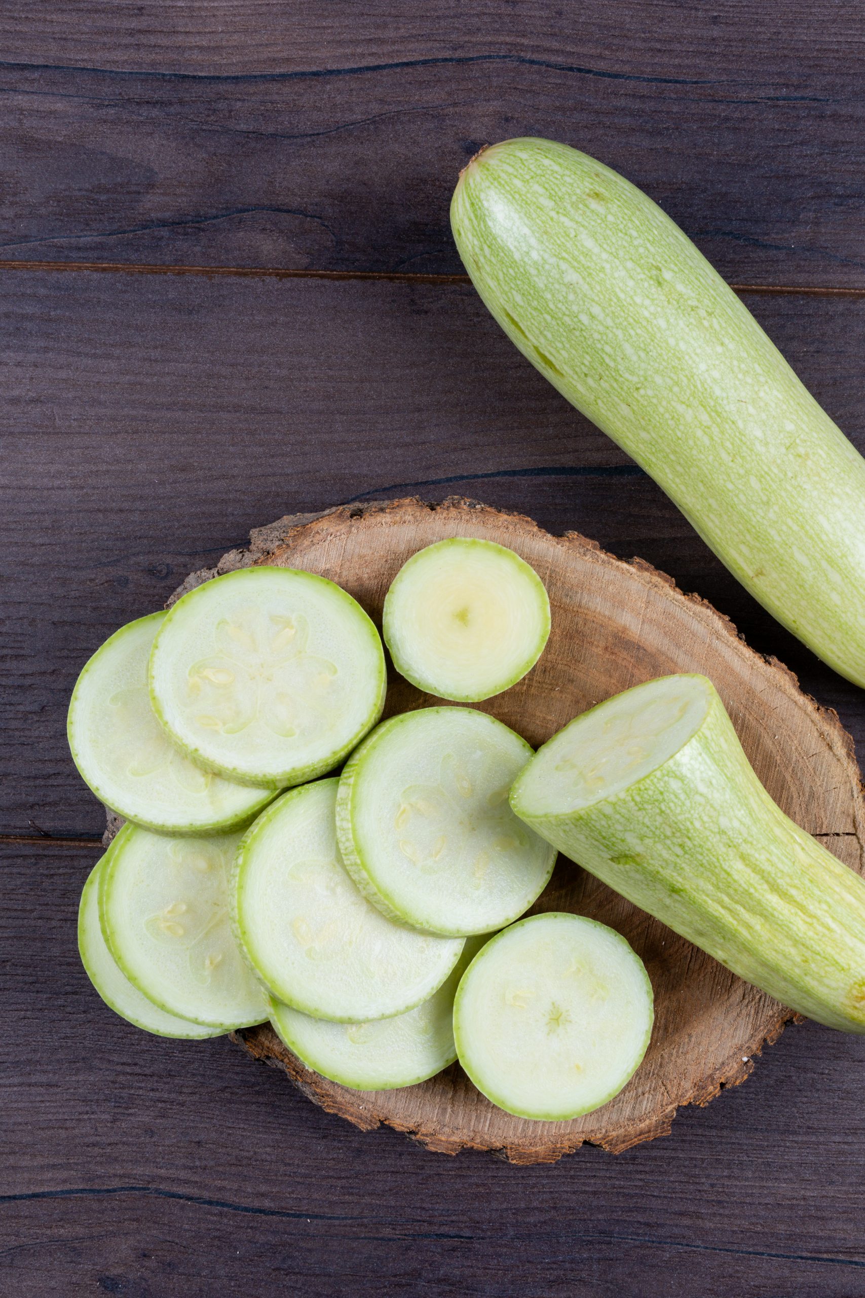 High angle view sliced zucchinis on stub and dark wooden background. vertical
